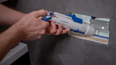 A man installs a Geberit flush valve in a concealed cistern (© Ben Huggler)