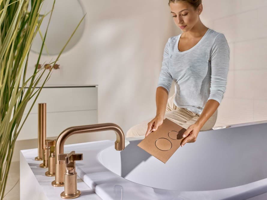 Woman in the bathroom with Sigma40 actuator plate in brushed copper, colour-matched to the fittings