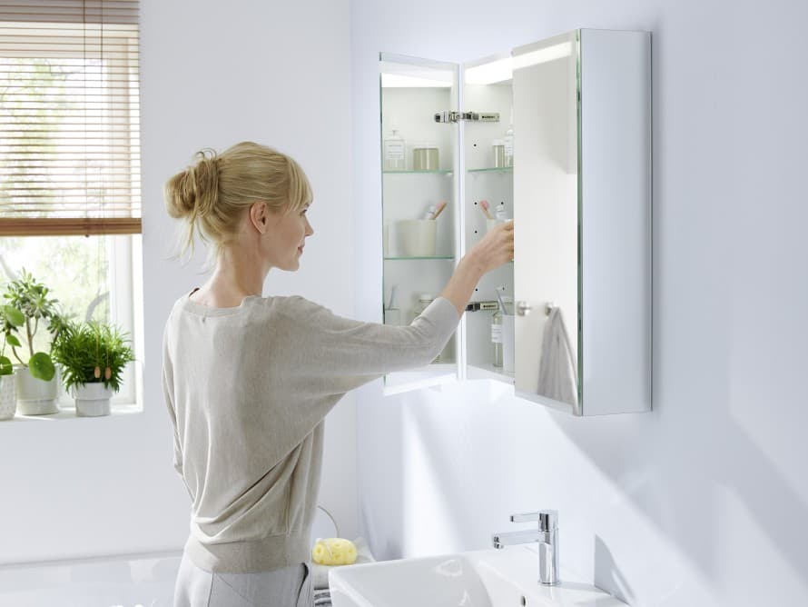 Woman looking at Geberit Option mirror cabinet with lighting Woman looking at Geberit Option mirror cabinet with lighting