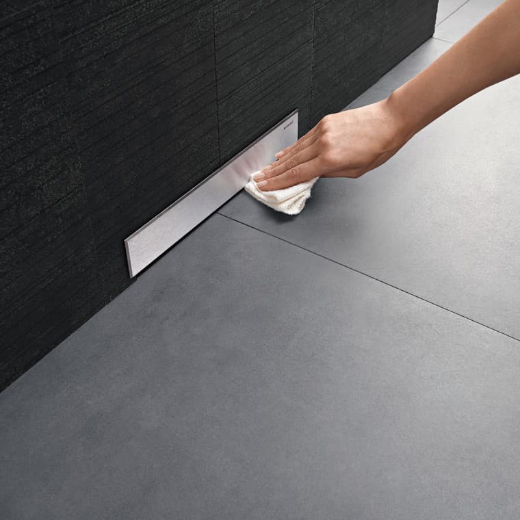 Hand cleans the cover of a Geberit wall drain Hand cleans the cover of a Geberit wall drain